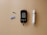 A blood glucose meter is centrally placed on a beige surface, displaying a reading of 103 mg/dL. To its left is a blue lancet for blood sampling, and a black test strip. On the right side is a white and gray lancing device.