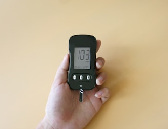a hand holding a digital thermometer on a yellow background