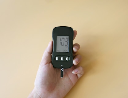 a hand holding a digital thermometer on a yellow background