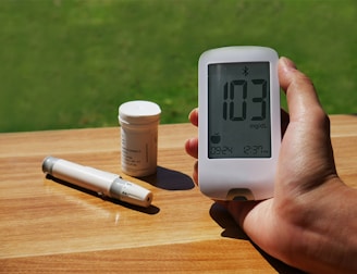 a person holding a thermometer next to a bottle of pills