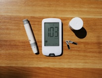 a wooden table topped with a smart phone and a pen