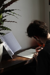 A person writing in a journal surrounded by plants.