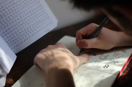 a person writing on a piece of paper with a pen