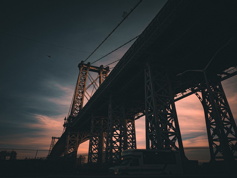 a truck is driving under a bridge at sunset