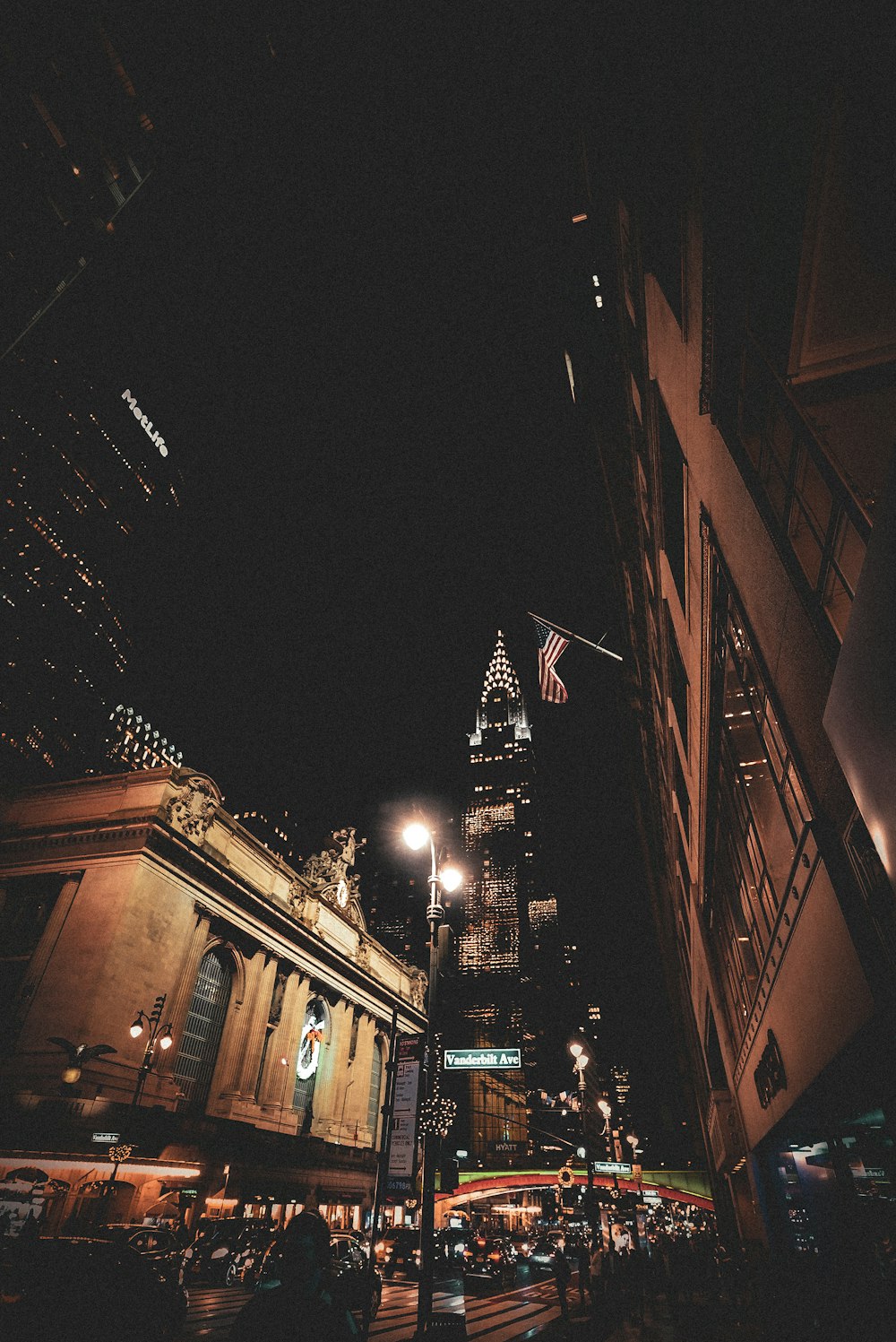 a city street at night with a tall building in the background