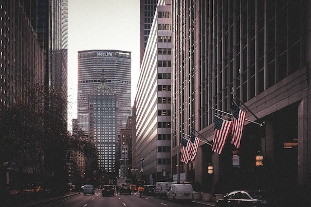 a city street lined with tall buildings and american flags
