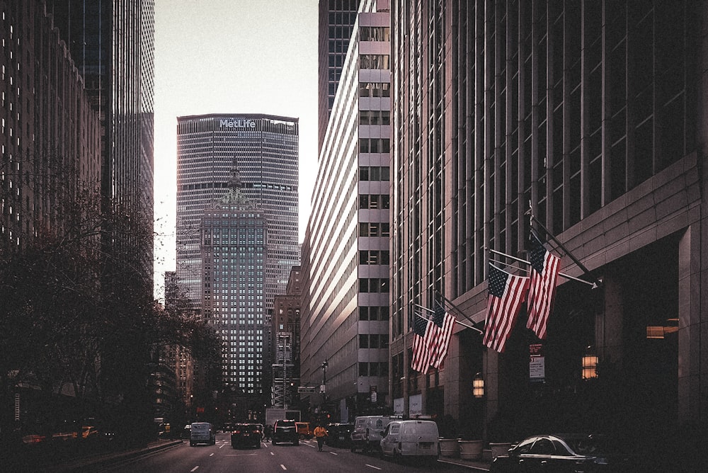 a city street lined with tall buildings and american flags