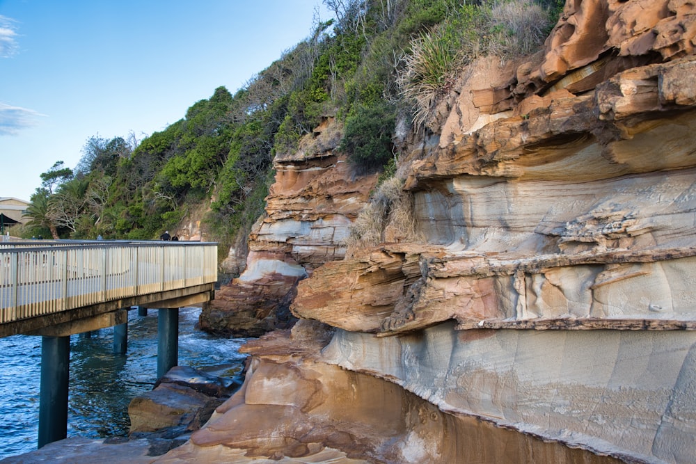 a bridge over a body of water next to a cliff