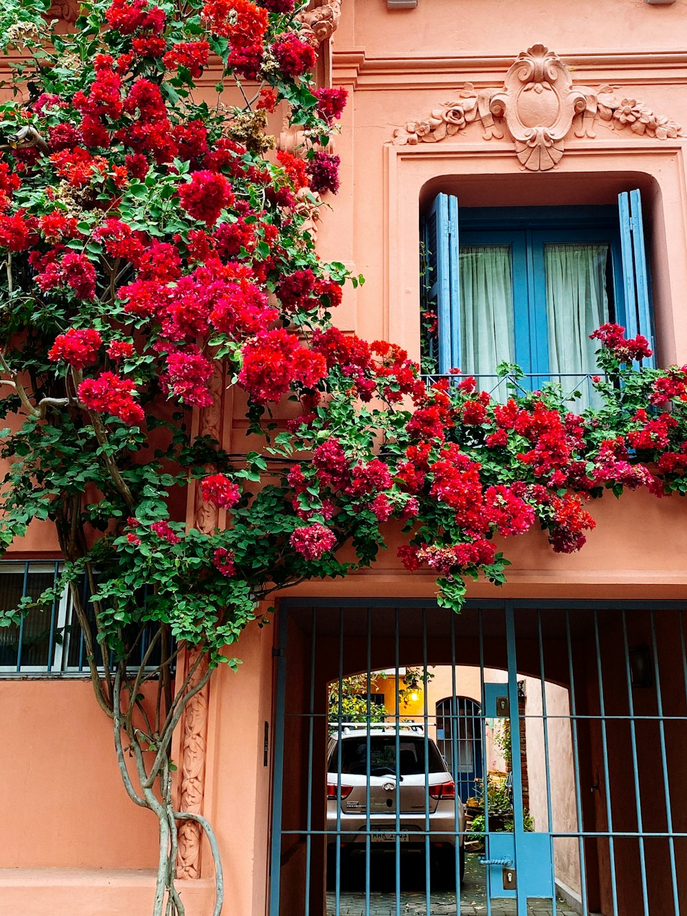 a pink building with a bunch of red flowers on it