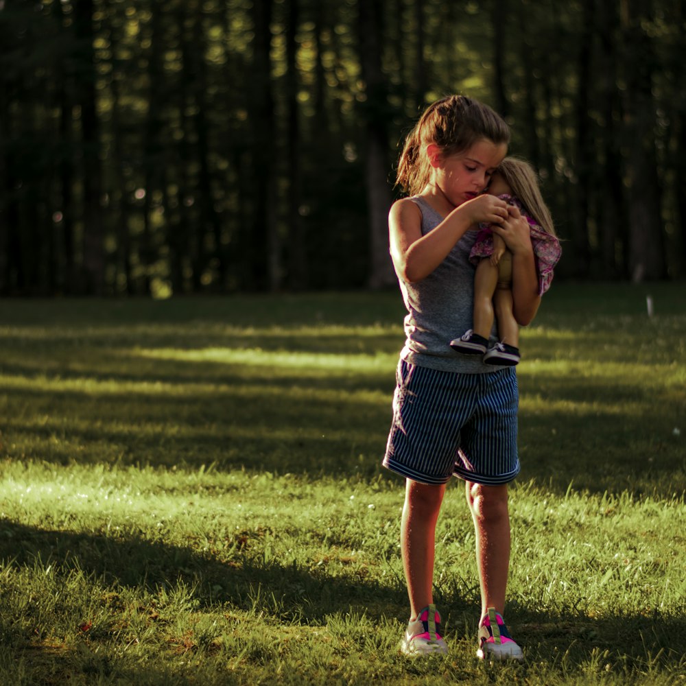 a little girl holding a stuffed animal in a field