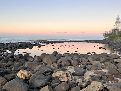 A serene fine art photo of a quiet coastal scene at dawn with pastel colors.