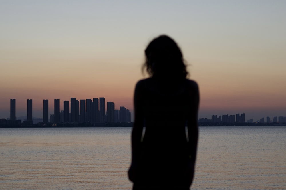 a woman standing in front of a body of water