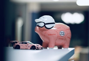 a pink piggy bank sitting on top of a table next to a pink car