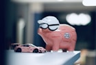 a pink piggy bank sitting on top of a table next to a pink car