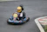 A joyful child wearing a helmet, driving a colorful kids kart on the track.