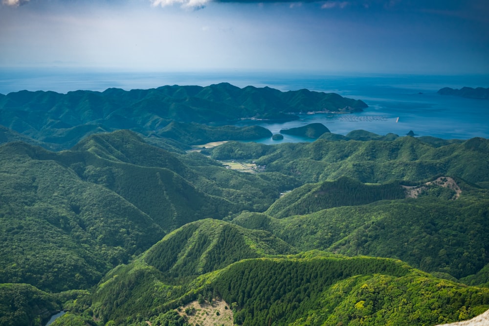 an aerial view of a mountain range with a body of water in the distance