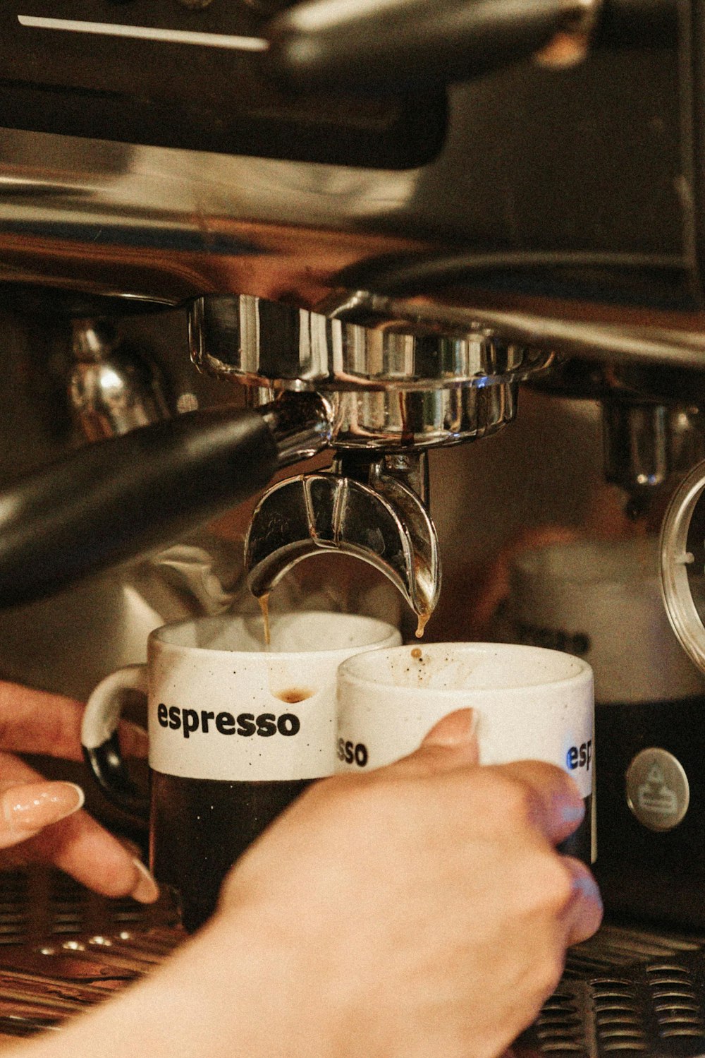 a person filling a cup of coffee from a coffee machine