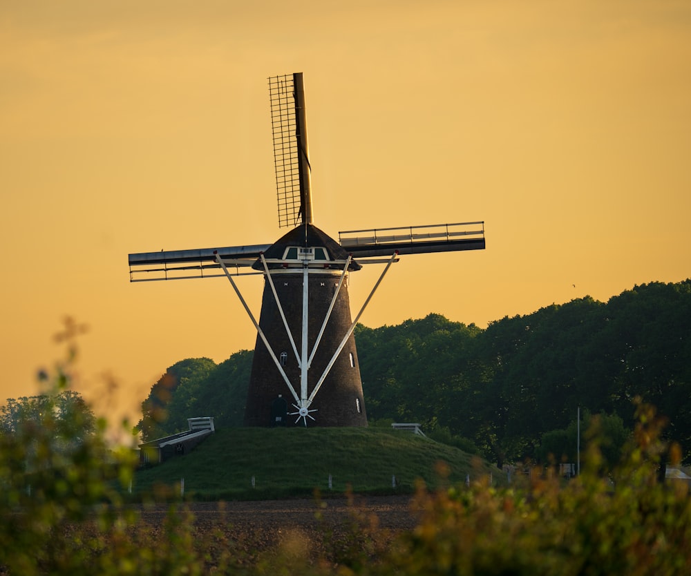 a windmill in a field with trees in the background