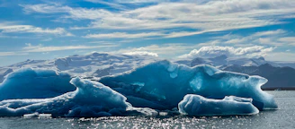 Black and white photo of massive icebergs floating in the calm waters of Disko Bay at sunset.
