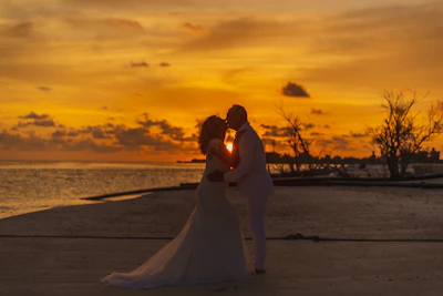 A couple exchanging vows on a serene beach at sunset, surrounded by close family.