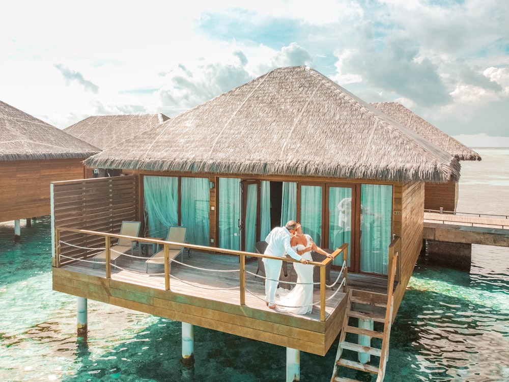 a man and a woman standing on a dock in front of a house