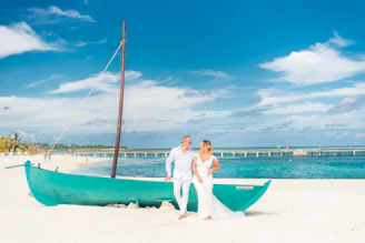 a man and woman standing next to a boat on the beach
