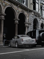 A vintage luxury car parked beside a modern architectural marvel.