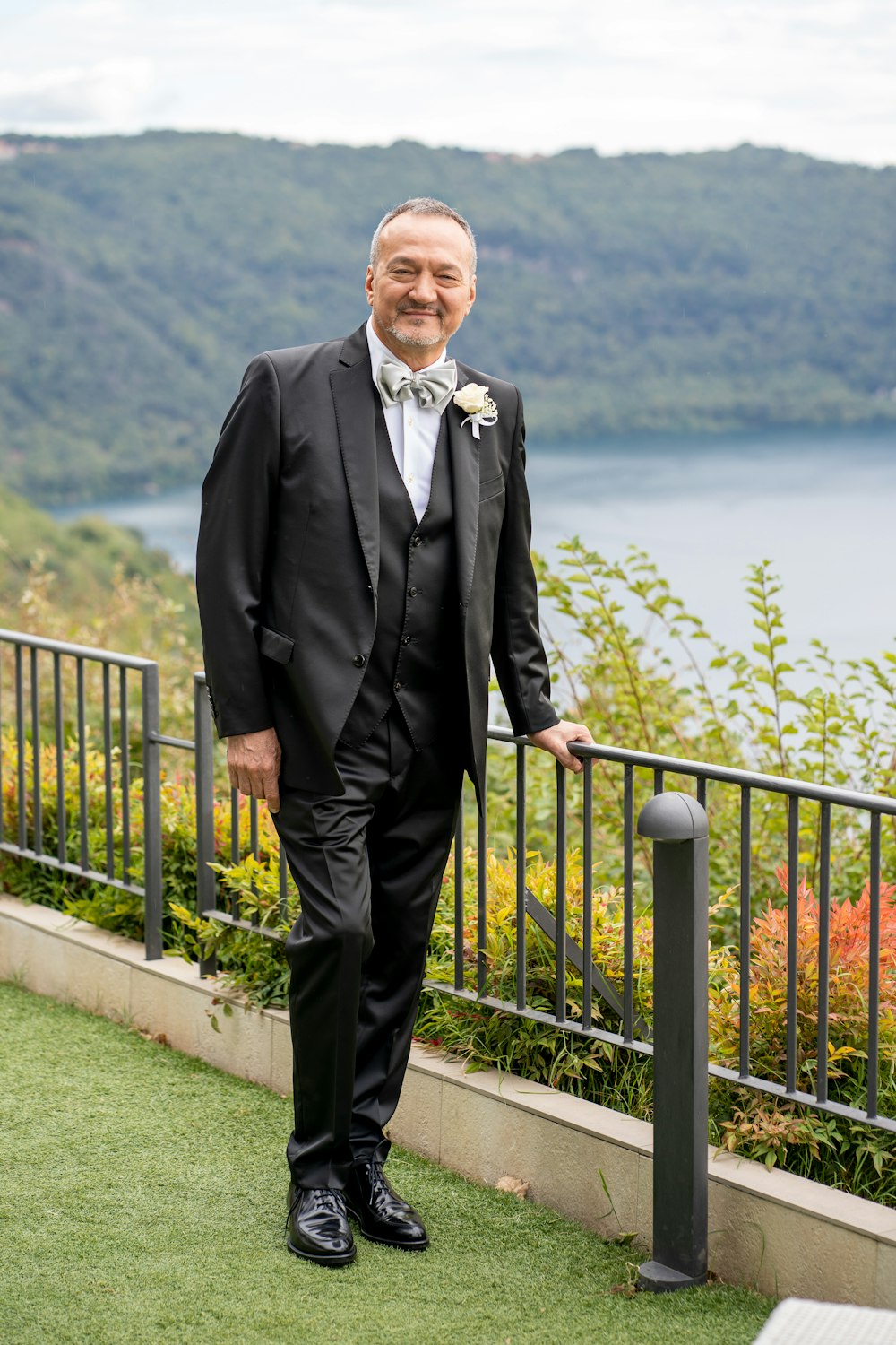 a man in a tuxedo standing next to a railing