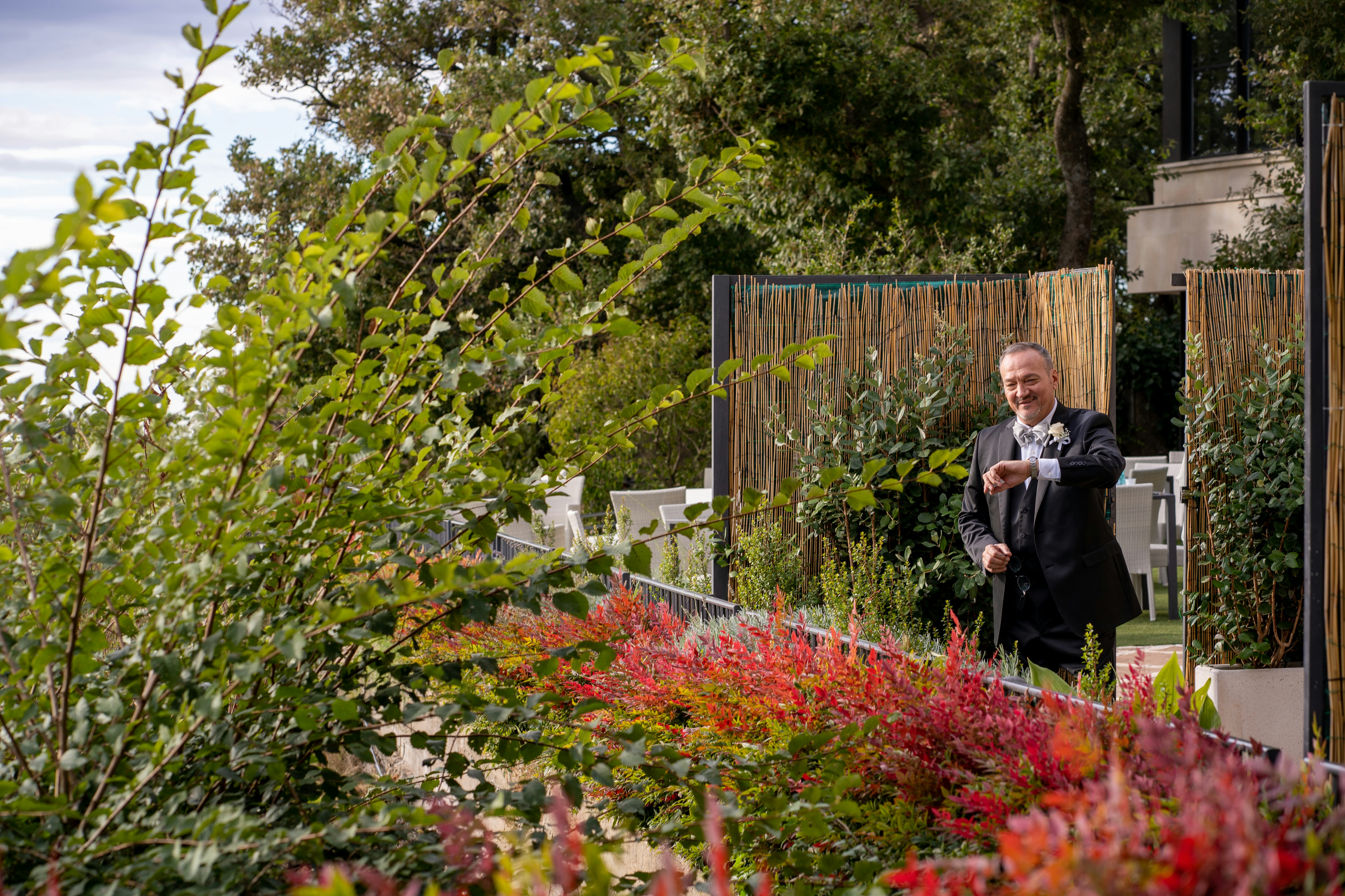 a man in a suit standing in a garden