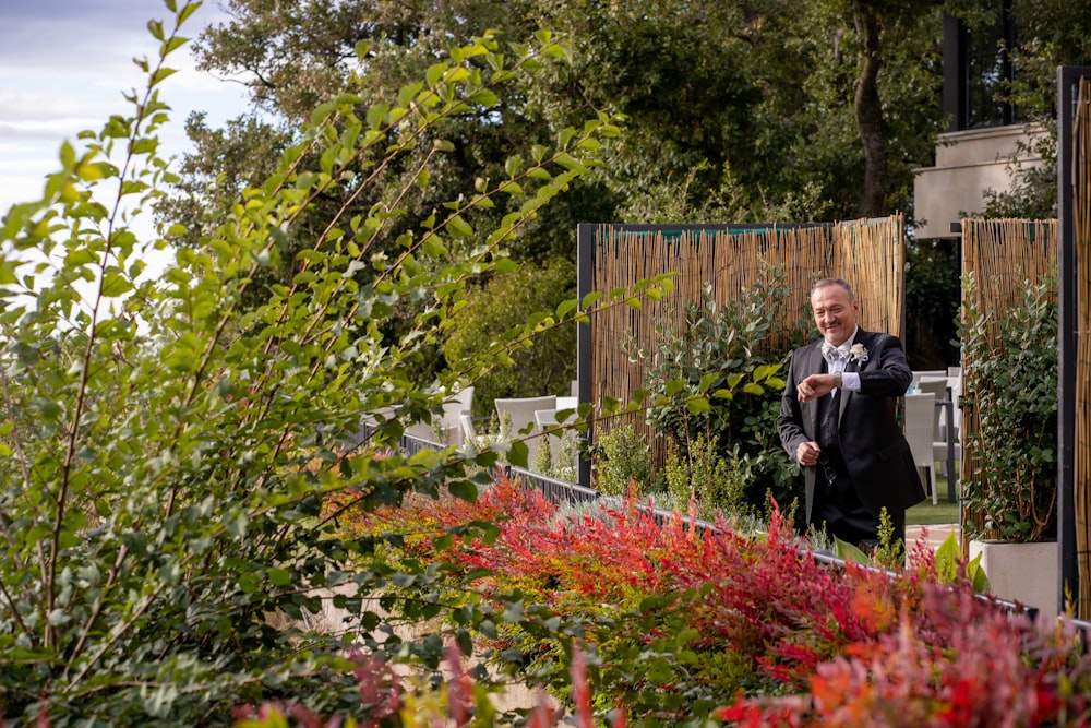 a man in a suit standing in a garden