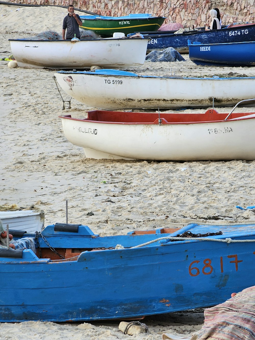 Un grupo de barcos sentados en la cima de una playa de arena