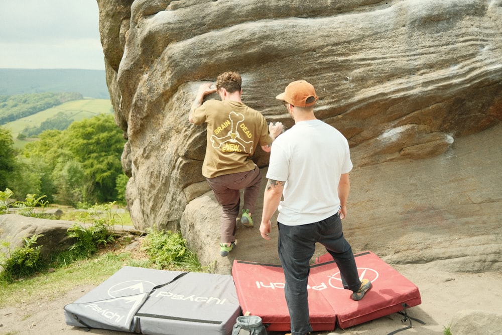 a couple of men standing on top of a rock