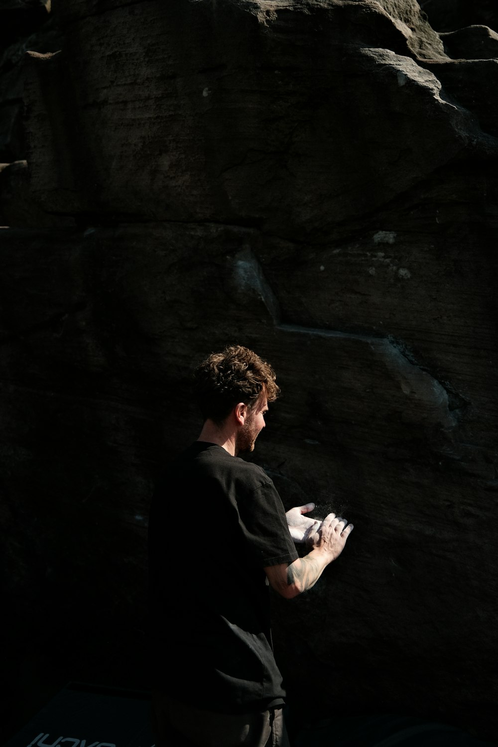 a man standing in front of a large rock