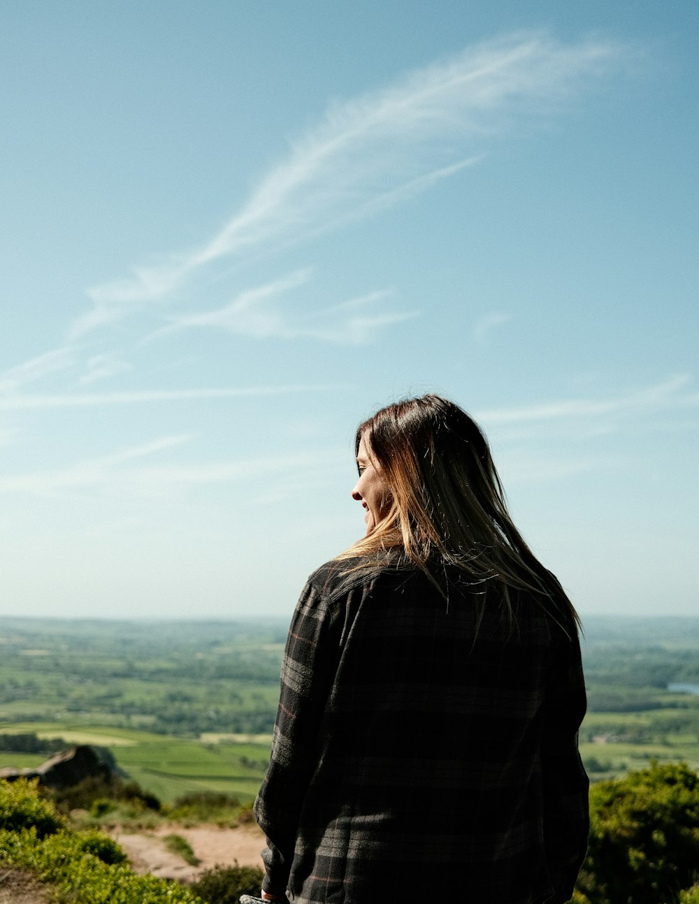 a woman standing on top of a lush green hillside