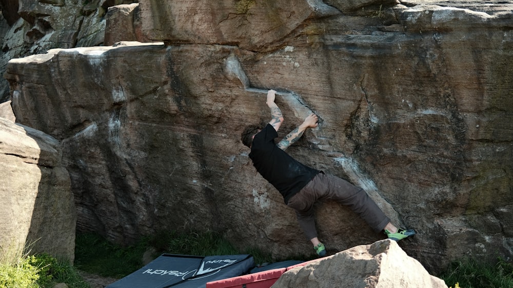 a man climbing up the side of a large rock