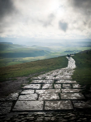 A serene view of pilgrims walking the ancient stone path of Camino de Santiago under soft morning light.
