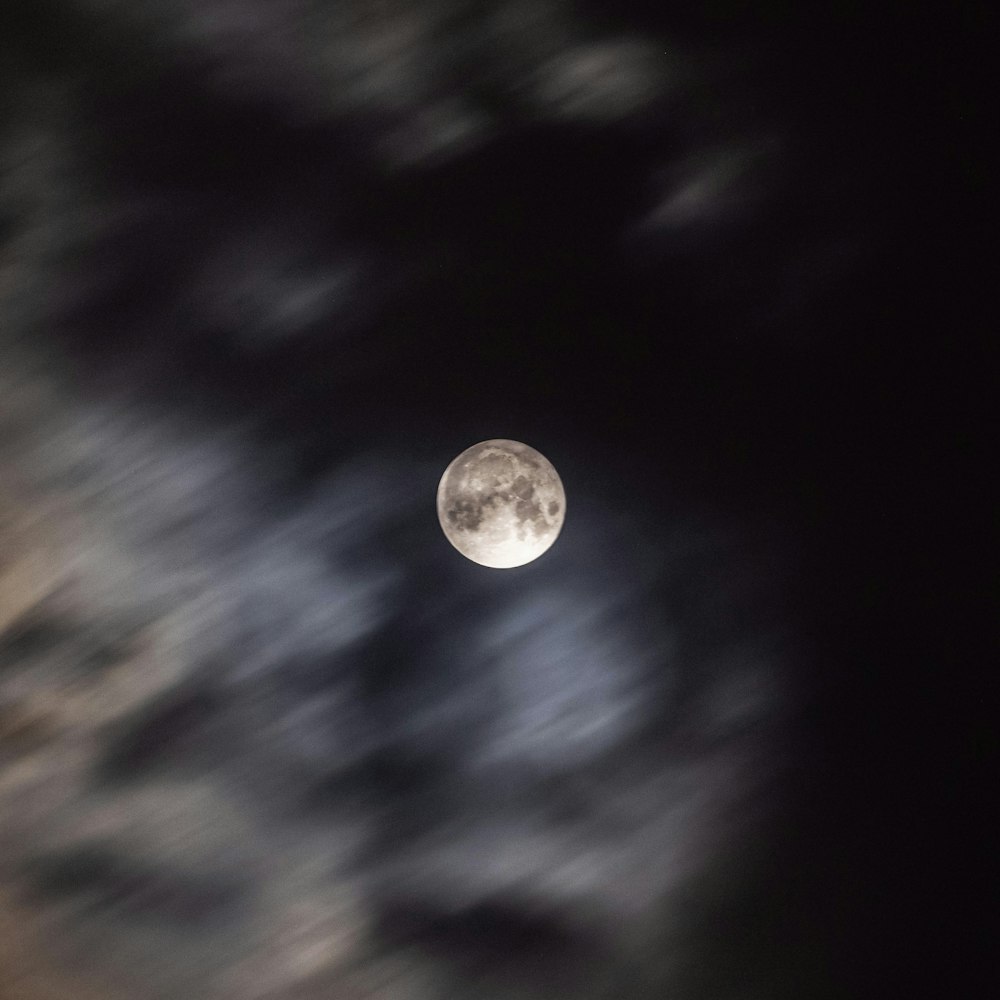 a full moon is seen through the clouds