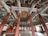 An intricately decorated interior space with colorful patterns on wooden columns and beams. The architecture features rich detailing on the ceiling and a harmonious blend of colors. The room has a spacious, symmetrical layout, with traditional Asian design elements throughout.