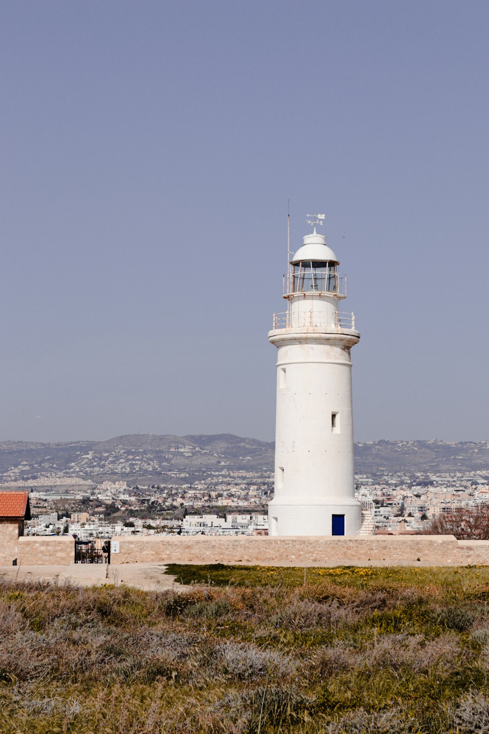 a white light house sitting in the middle of a field