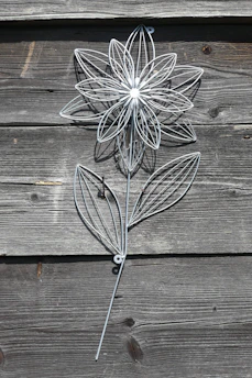 Decorative metal floral wall art with intricate petal details in warm tones.