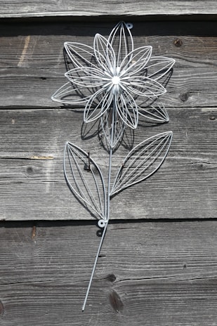 Abstract metal decor with intricate curves and a rustic patina finish hanging on a white wall.