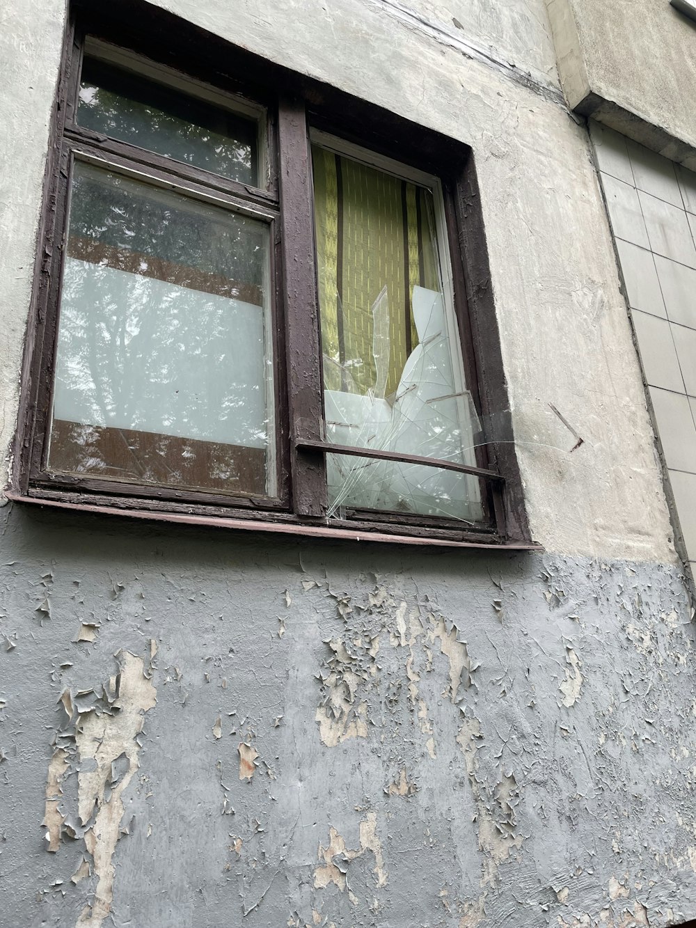 a broken window on a building with a broken curtain