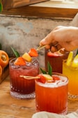 Colorful fruit garnishes beside freshly made juice drinks.