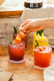 a person putting a piece of fruit on top of a drink