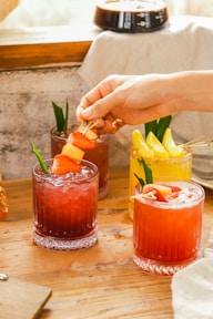 a person putting a piece of fruit on top of a drink
