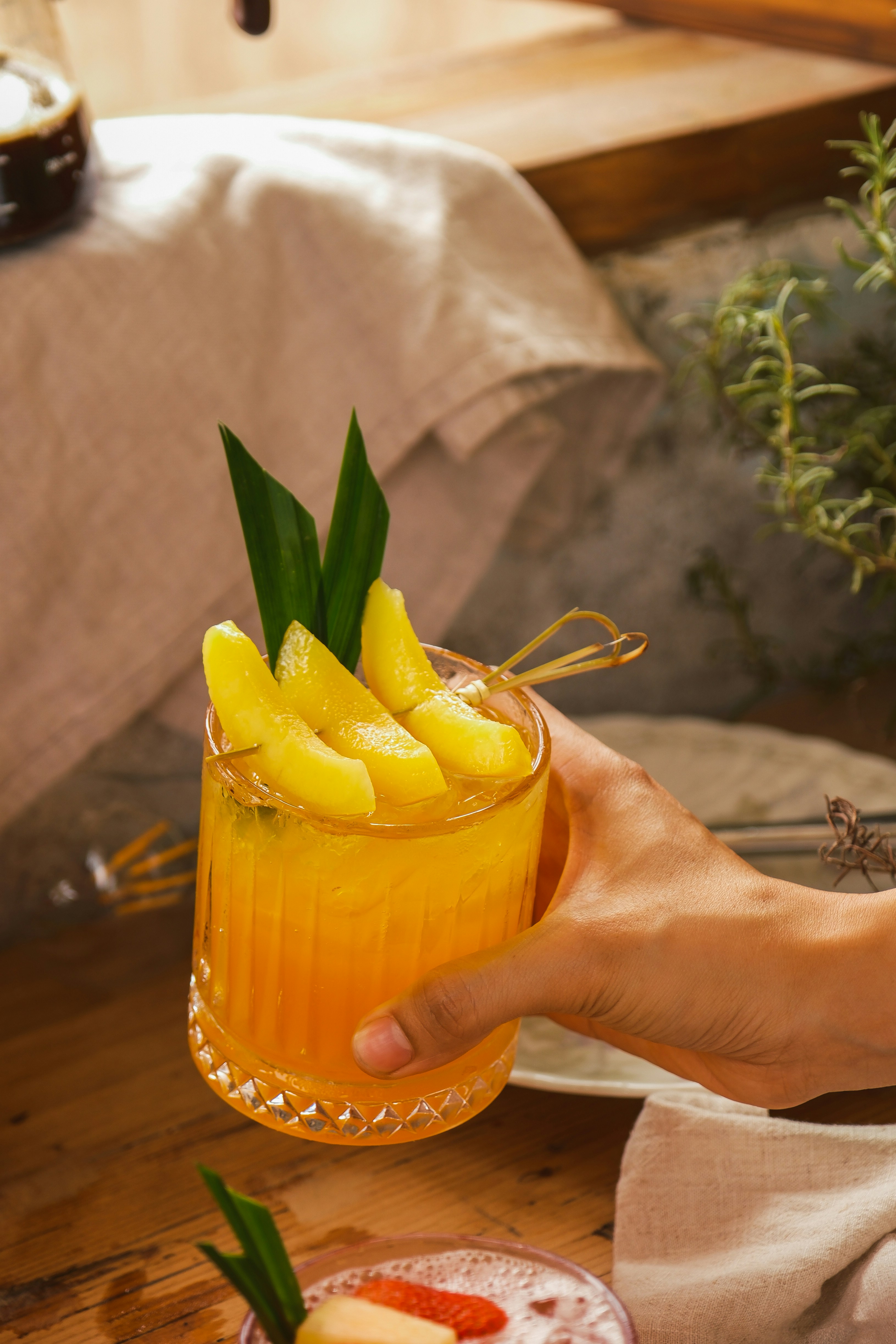 Fresh orange mango juice in glass with mango slices on bright surface