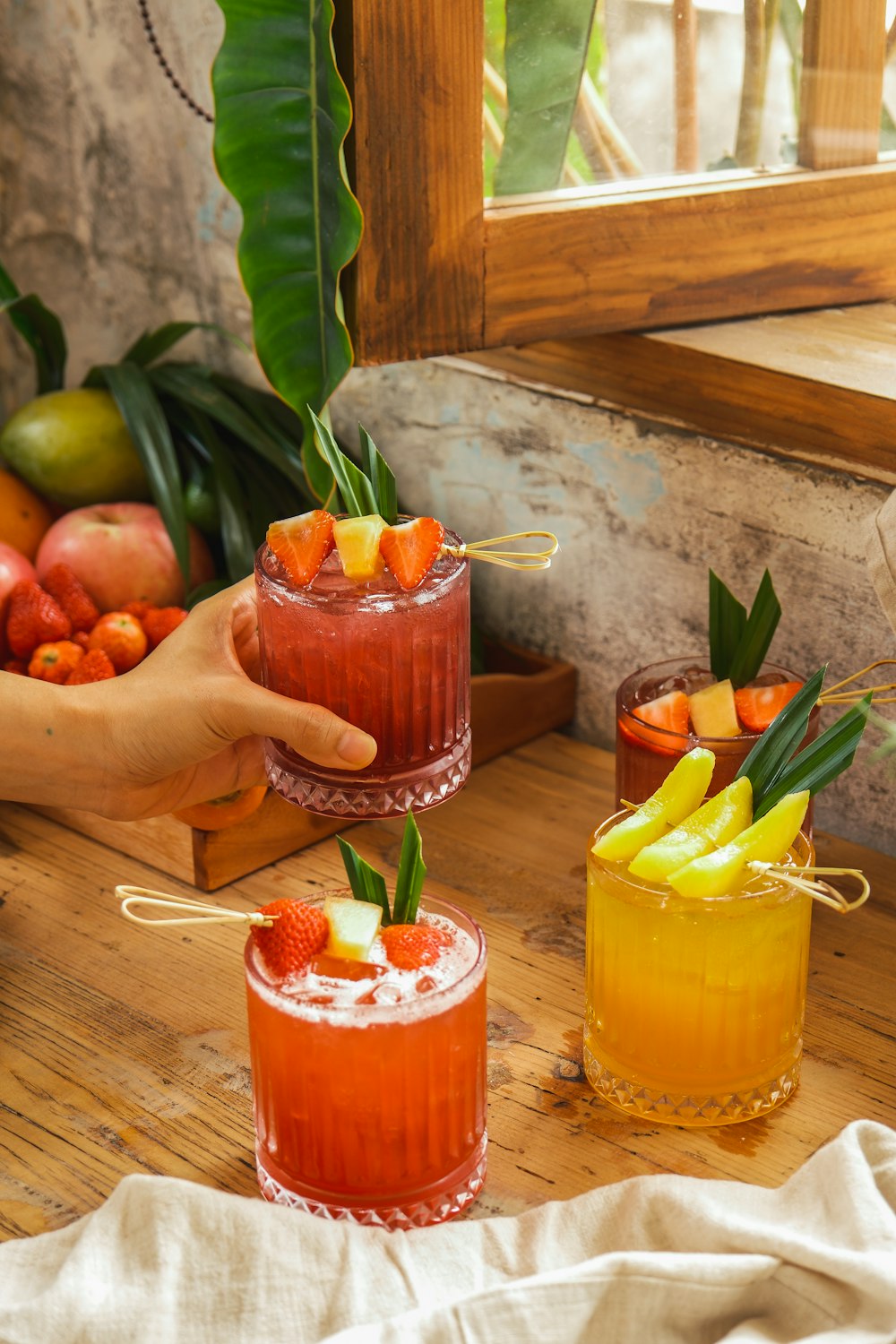 a person holding a glass with a fruit drink in it