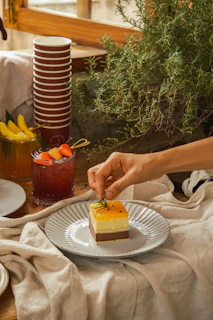 A professional caterer in black attire arranging a dessert table adorned with thyme sprigs.