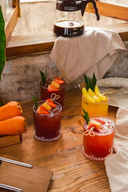 A colorful assortment of refreshing beverages including water, soda, and coffee cups on a wooden table.