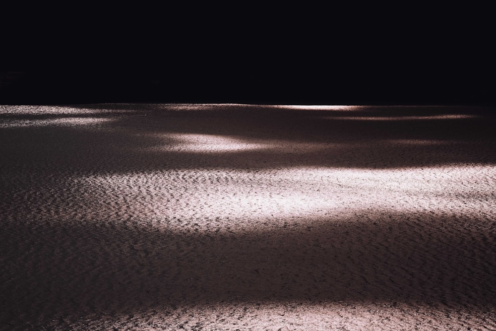 a black and white photo of the sun shining on the sand